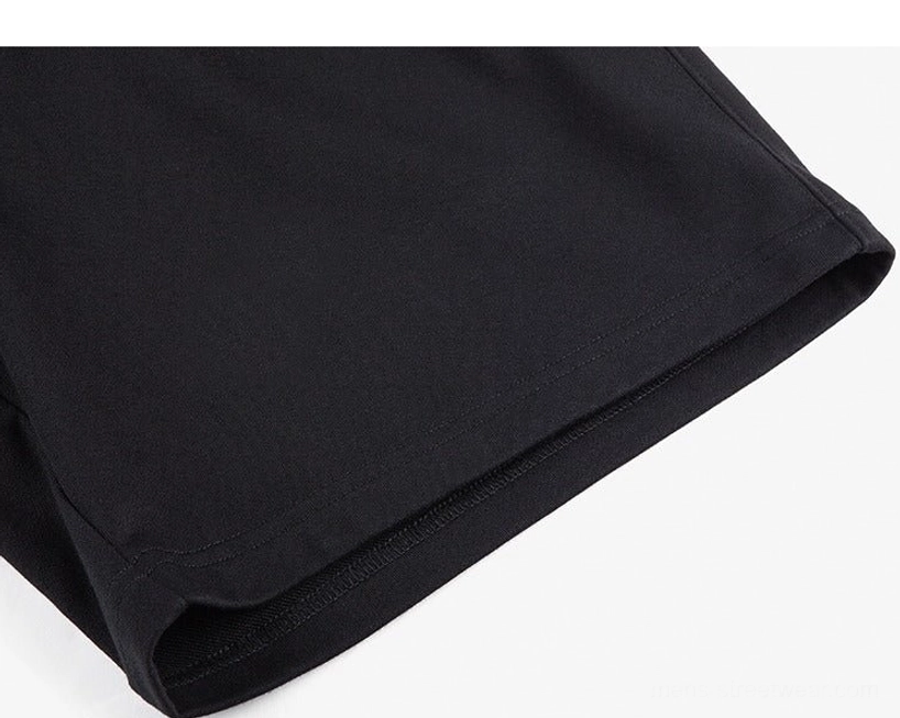 Close-up view of the clean finished hem on black oversized cotton sweat shorts with neat seam construction