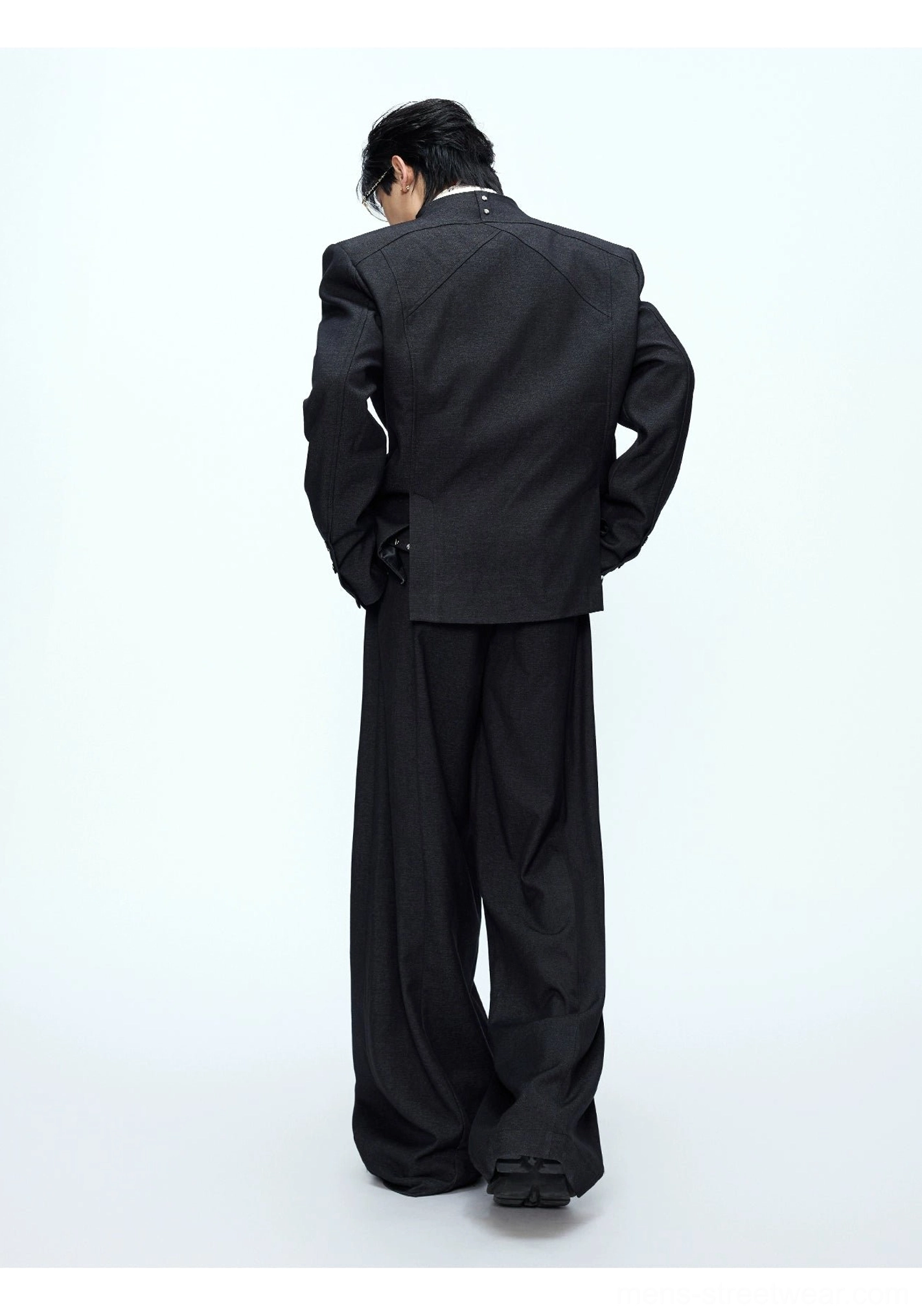 Back view of black oversized tailored blazer and high-waisted wide-leg pants in white studio