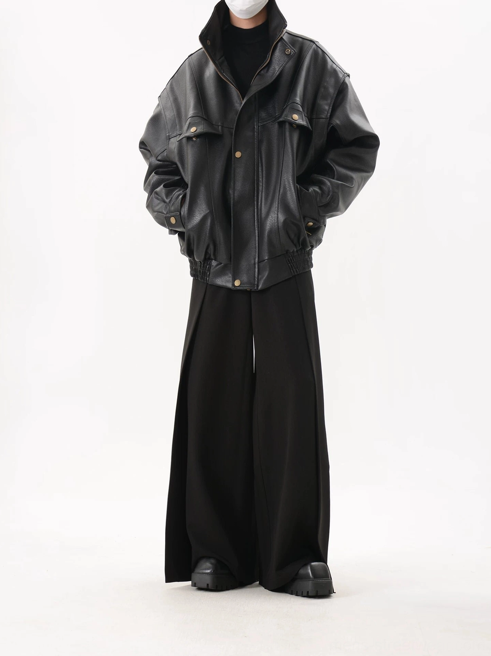 Full-body front view of a black oversized utility bomber jacket styled with wide-leg trousers, chunky platform shoes, and a black turtleneck for Seoul streetwear fashion