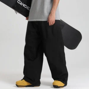 Black oversized waterproof snow pants with drawstring waist and adjustable cuffs styled for skiing and modern streetwear