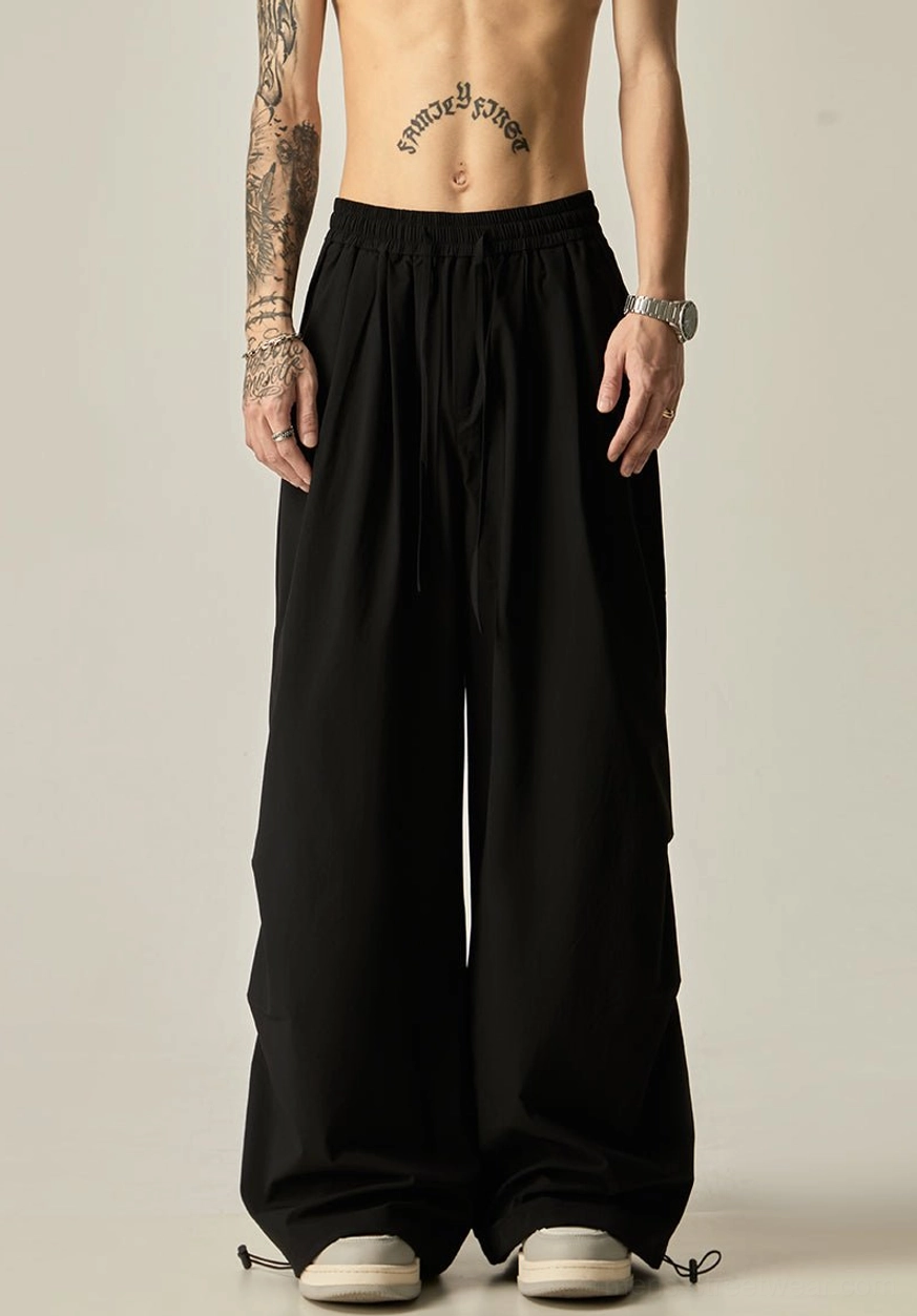 Black oversized wide leg pants for men shown from the front with a relaxed fit and minimalist elasticated waistband