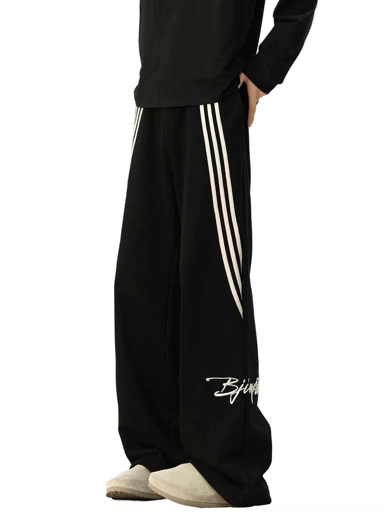 Black oversized wide-leg track pants with contrasting white side stripes, white script embroidery, relaxed Korean streetwear silhouette, and casual athletic styling