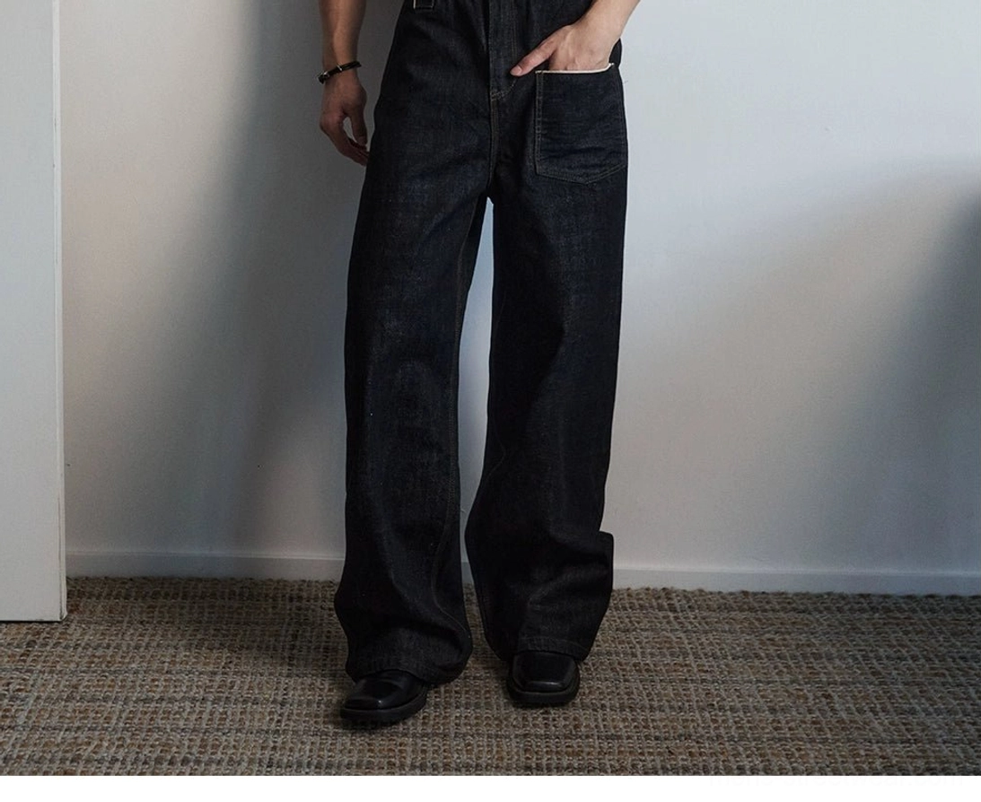 Side view of black oversized wide leg utility jeans with contrast-stitched front pocket and pooling denim hem