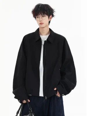 Black oversized zip-up streetwear jacket shown from the front with dropped shoulders, wide sleeves, shirt collar, white T-shirt, and dark wide-leg jeans