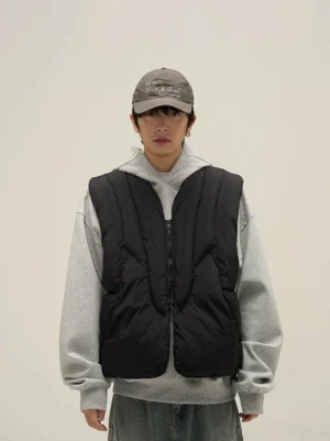 Close-up front view of a black padded quilted puffer vest showing wavy stitching front zipper and relaxed streetwear fit