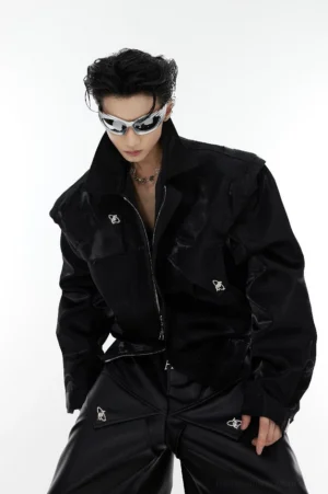 Black padded shoulder vegan leather cropped streetwear jacket front view with glossy finish, zipper closure, notched lapel and metal button details