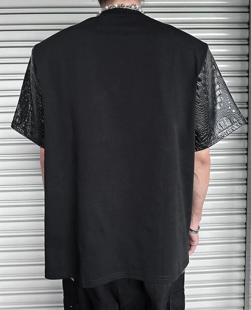Back view of black paneled streetwear T-shirt with solid cotton back, textured faux-leather short sleeves, and relaxed silhouette