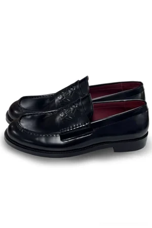 Black patent leather embossed penny loafers for men in three-quarter top view showing glossy finish, rounded square toe, and wine-red lining