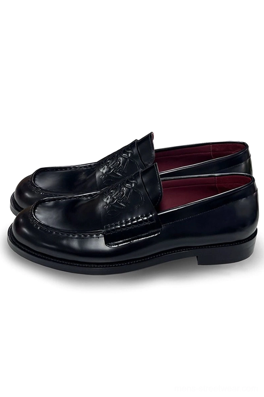 Black patent leather embossed penny loafers for men in three-quarter top view showing glossy finish, rounded square toe, and wine-red lining