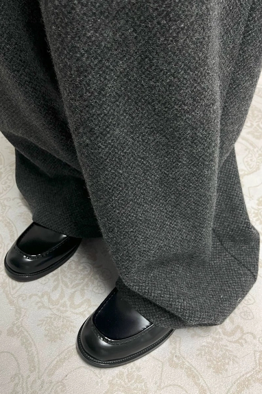Black glossy embossed penny loafers styled with grey wool tailored trousers in a refined modern menswear look