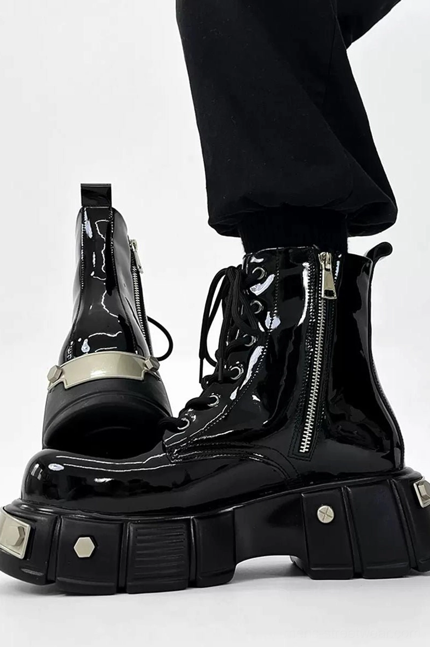 Three-quarter side view of black patent leather platform combat boots with heel pull tab, side zipper, silver rivets, and chunky rubber outsole