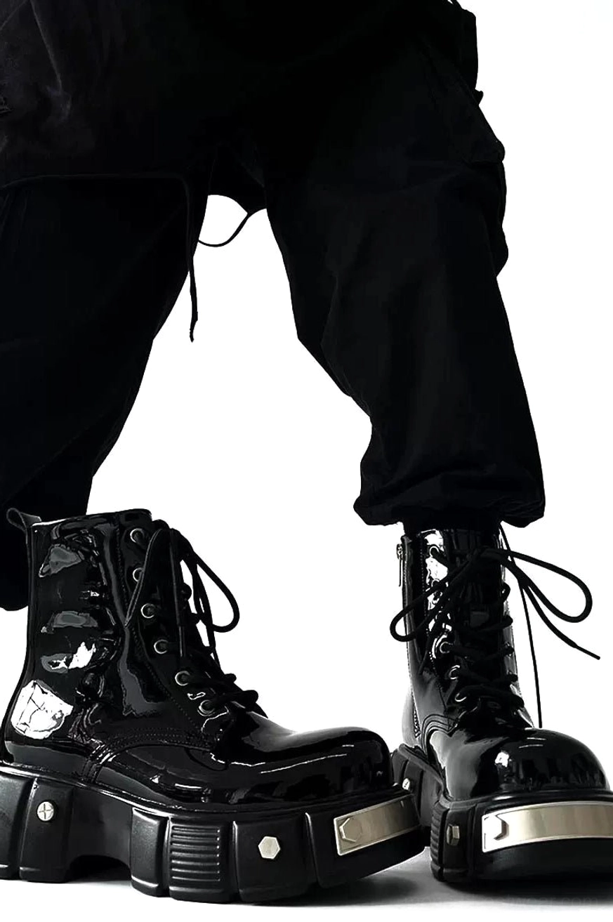 Front low-angle streetwear outfit view of black patent leather platform combat boots with silver sole hardware and cropped cargo pants