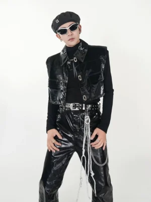 Men wearing a black patent PU cropped utility vest with glossy finish, structured shoulders, metal hardware, and punk streetwear styling in a white studio
