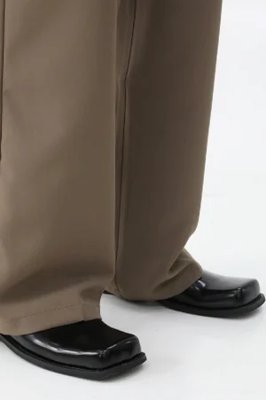 Model wearing black patent square-toe mules with brown wide-leg trousers, highlighting the polished leather finish, low flat sole, and contemporary Seoul-inspired streetwear styling