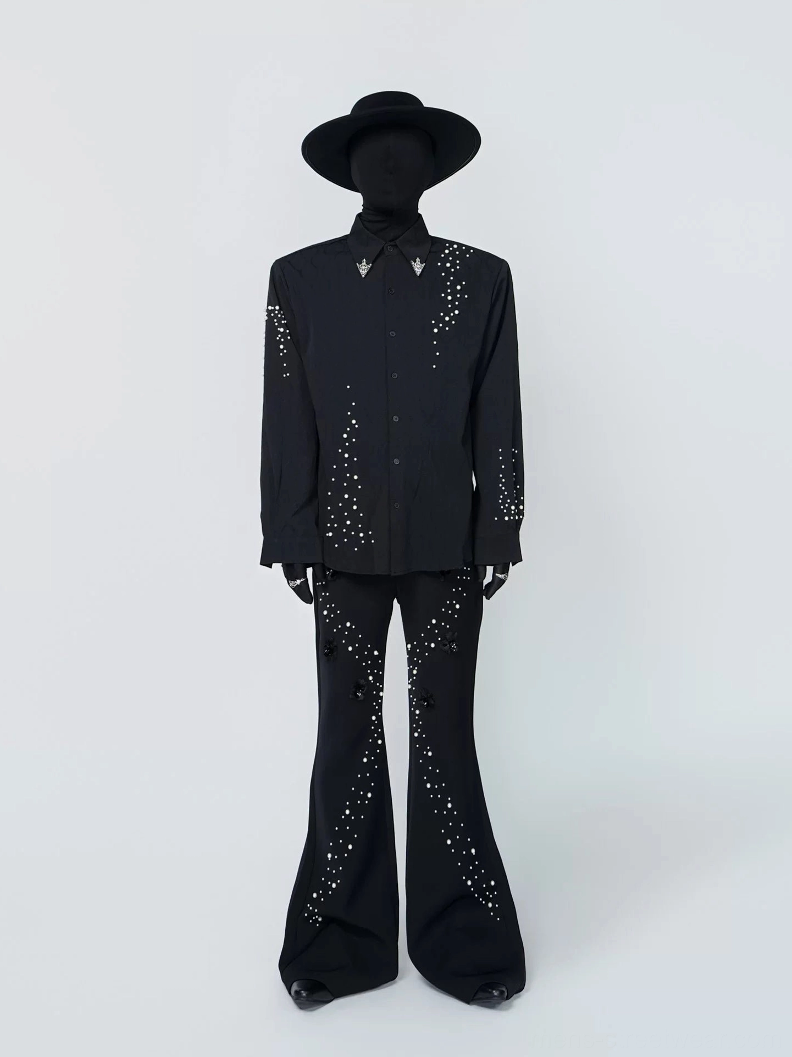 Full front view of a black pearl-studded Western-inspired shirt with pointed collar, metal triangle collar hardware, and scattered rhinestone decoration