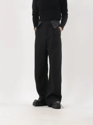 Low-angle front view of black pinstripe-trim wide-leg trousers styled with a black turtleneck and chunky leather shoes in a white studio