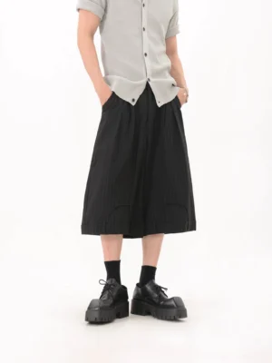 Front view of black pinstripe wide-leg culotte pants showing pleated waistband, relaxed cropped fit, side pockets, and platform shoe styling