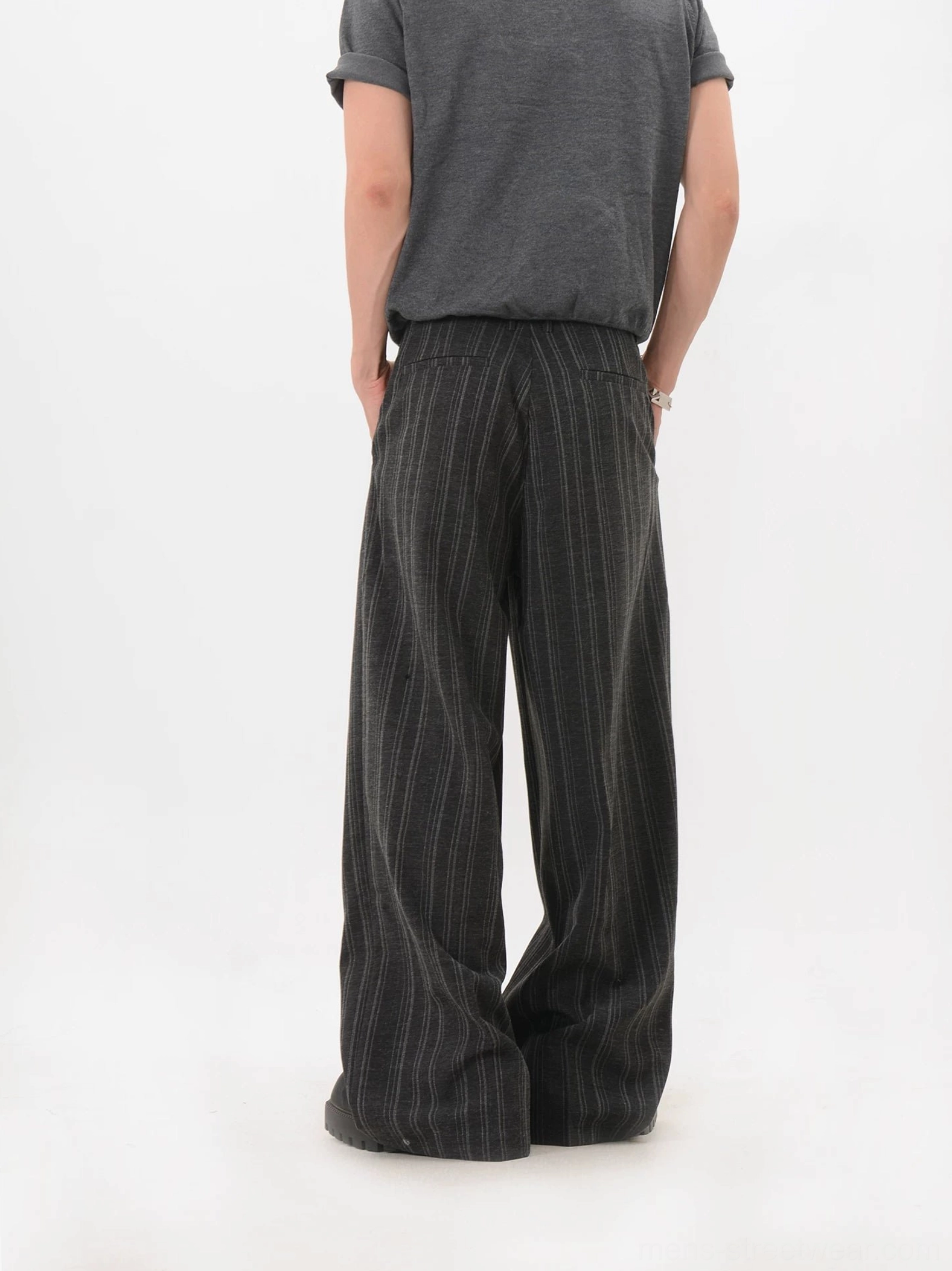 Rear three-quarter view showing the draped wide-leg silhouette of black pinstripe trousers