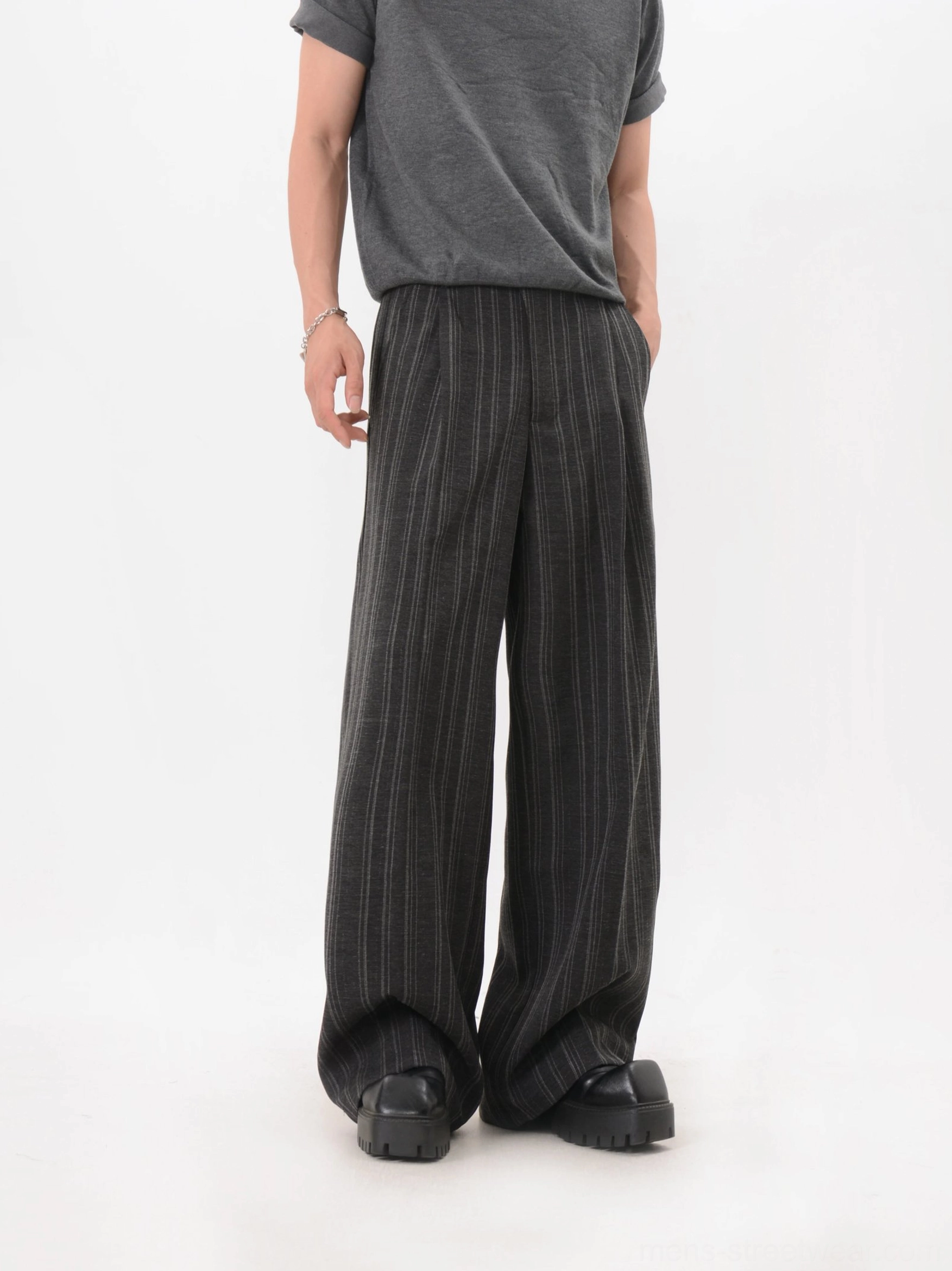 Back view highlighting the clean tailored finish and wide drape of black pinstripe trousers