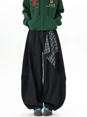 Front full-body view of black plaid tie barrel leg denim pants styled with a green graphic zip hoodie and retro sneakers