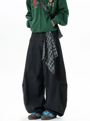 Three-quarter front view of black oversized barrel denim jeans with grey plaid waist tie detail and crossbody bag styling