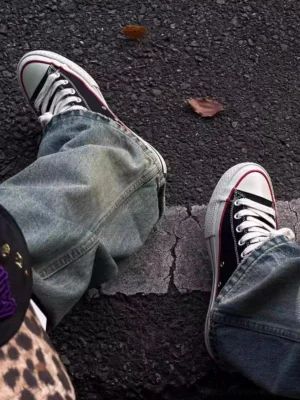 Black platform canvas streetwear sneakers worn with loose blue denim jeans in an outdoor asphalt street styling view