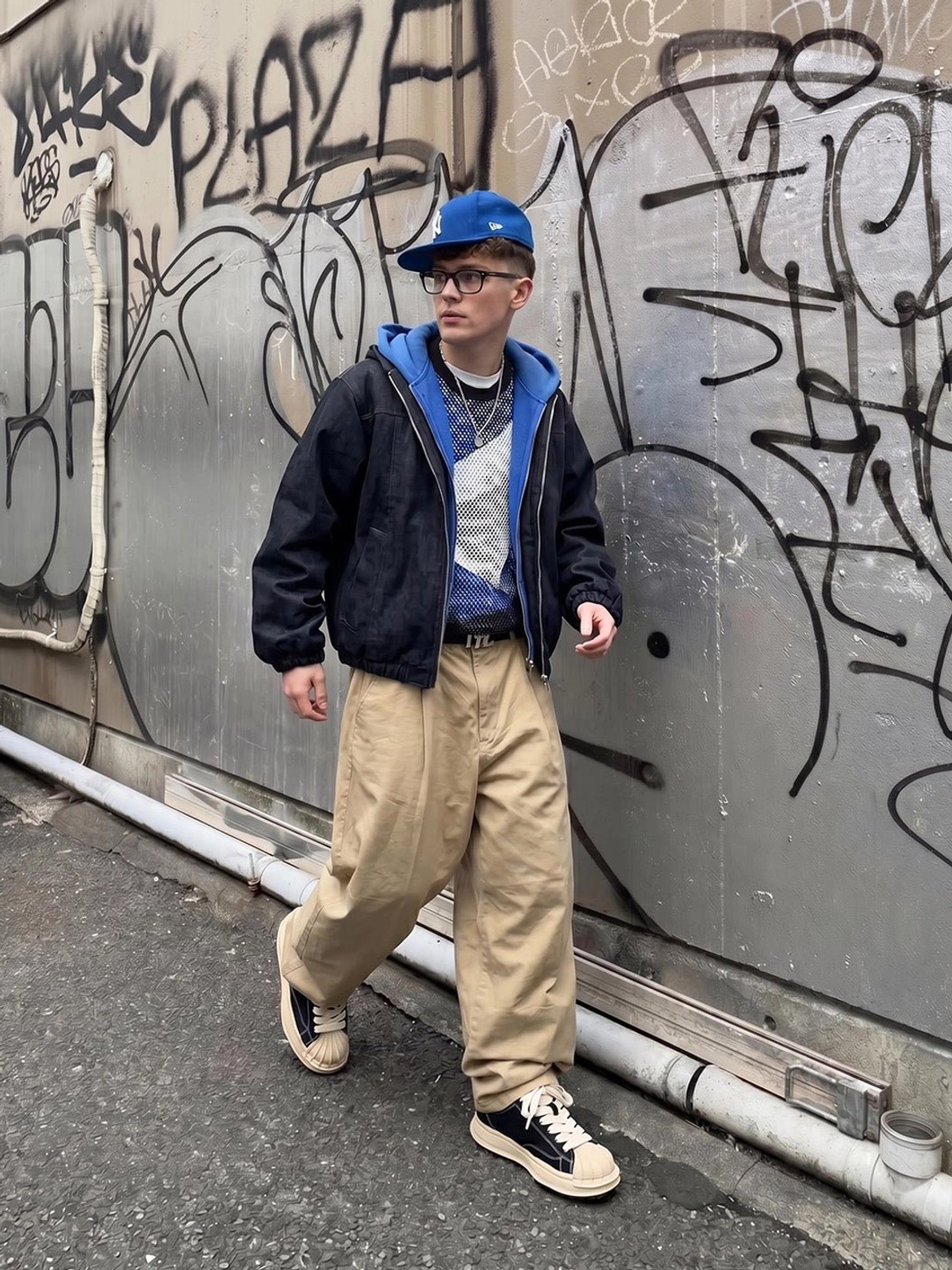 Male model styling distressed black shell-toe platform sneakers with layered jacket and khaki cargo pants