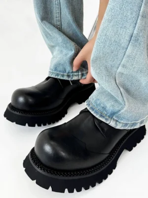Black platform derby shoes worn with washed denim showing the rounded toe, polished upper and chunky rubber sole