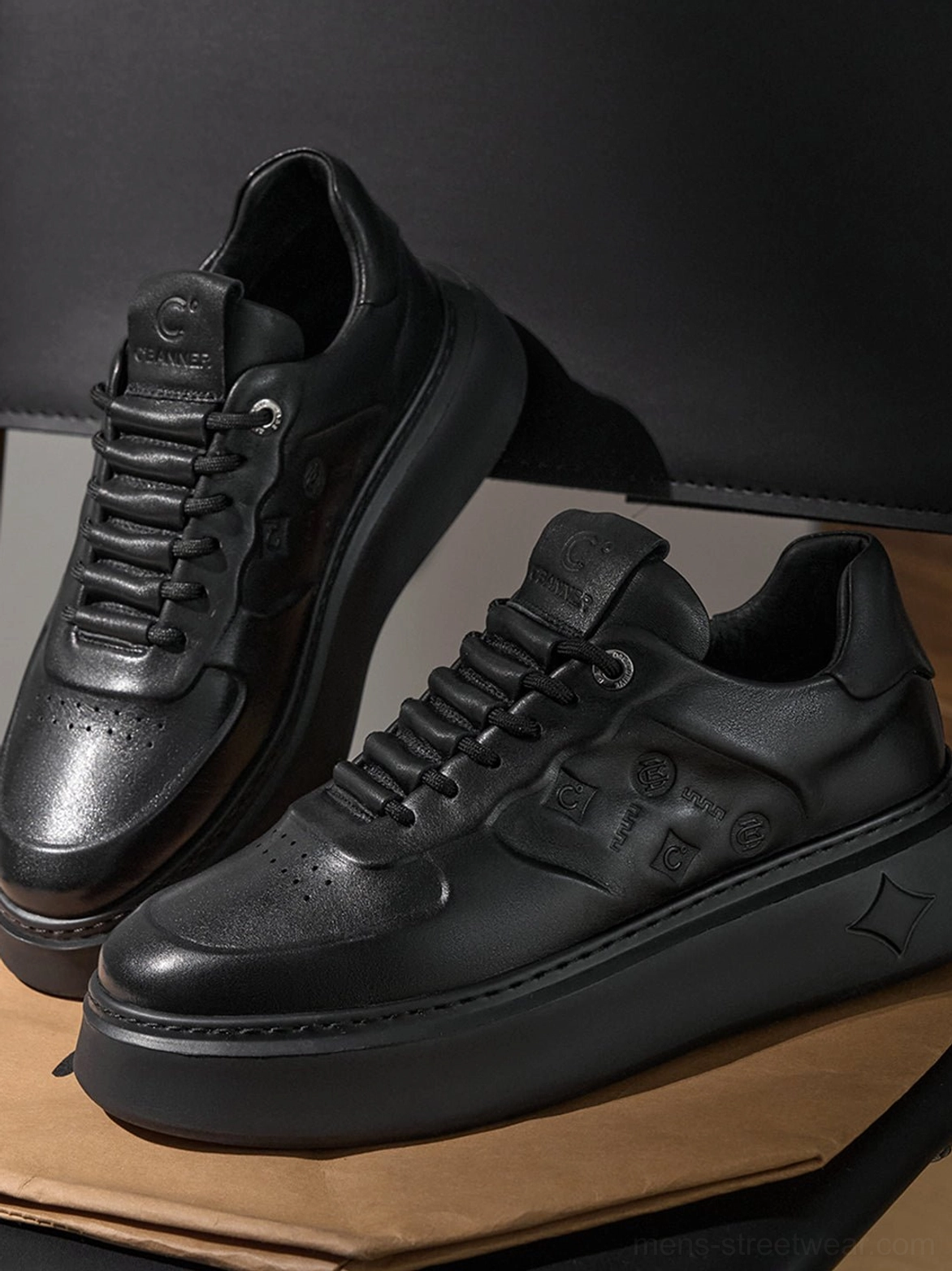 Black platform leather-look sneakers displayed in three-quarter view with lace-up closure and perforated toe box