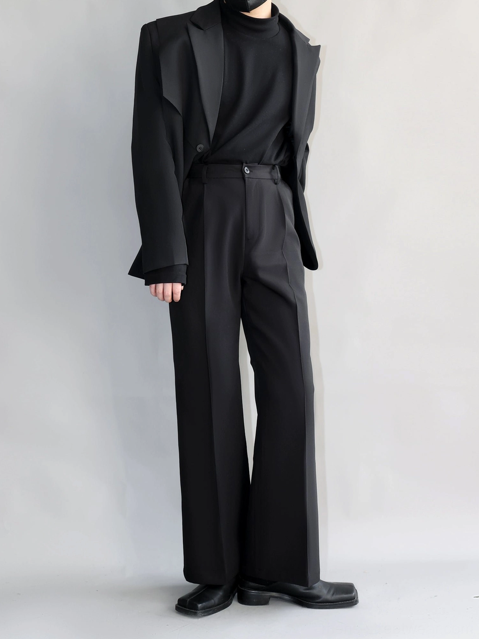 Black pleated tailored trousers with buttoned waistband front crease and full-length straight-leg silhouette front view