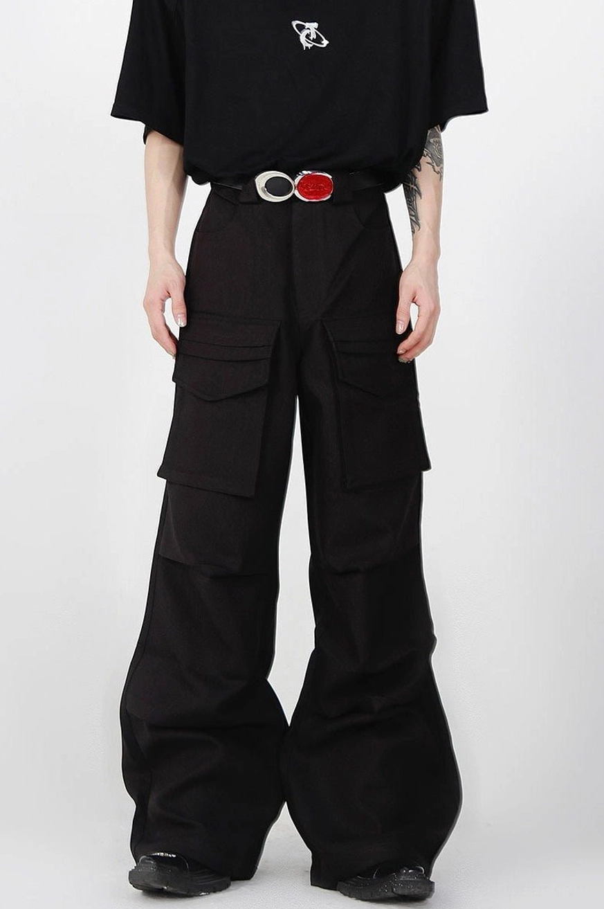 Black pleated wide-leg cargo pants shown from the front with high waist, dual flap cargo pockets, oversized fit, and minimalist urban streetwear styling