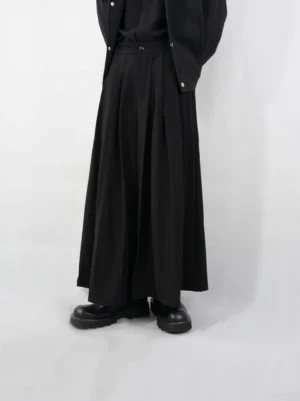 Front view of black pleated wide-leg palazzo pants showing the high-rise waistband, buckle detail, and full-length draped silhouette