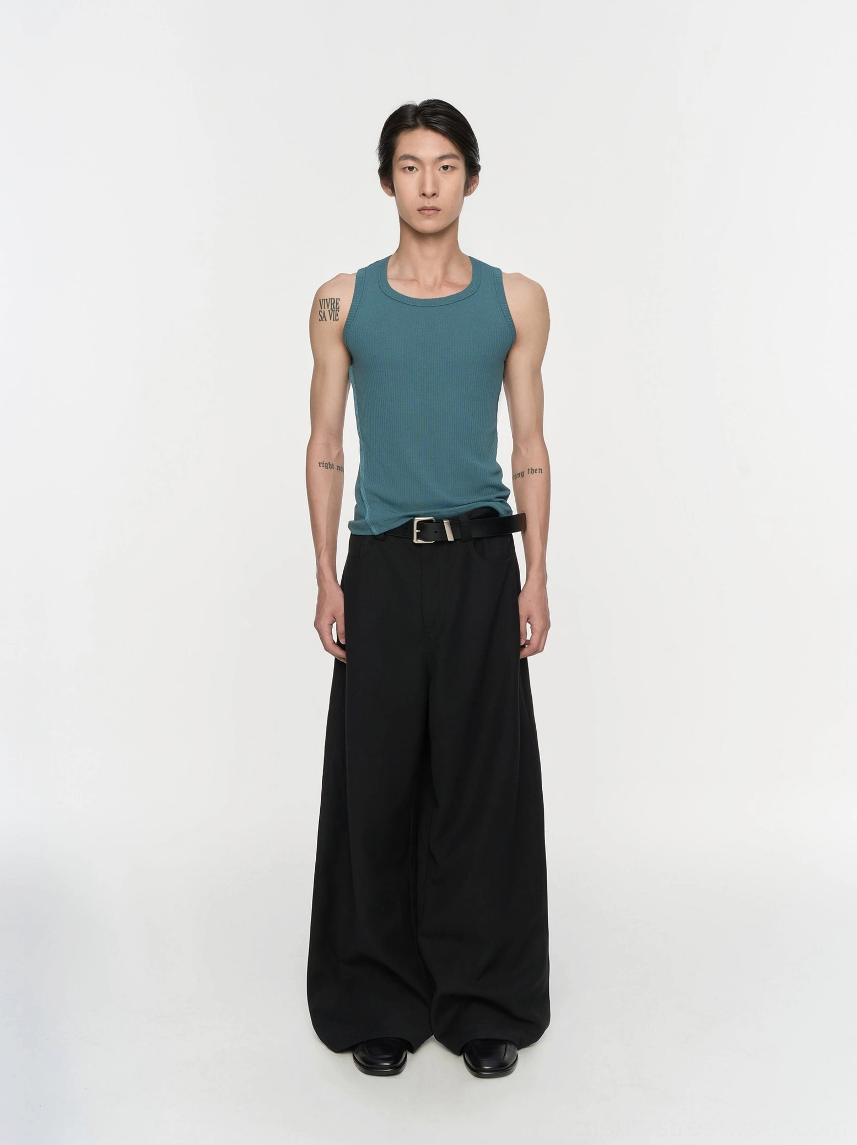 Black pleated wide-leg trousers shown in a full-body front view with a relaxed Korean streetwear silhouette and smooth matte suiting fabric