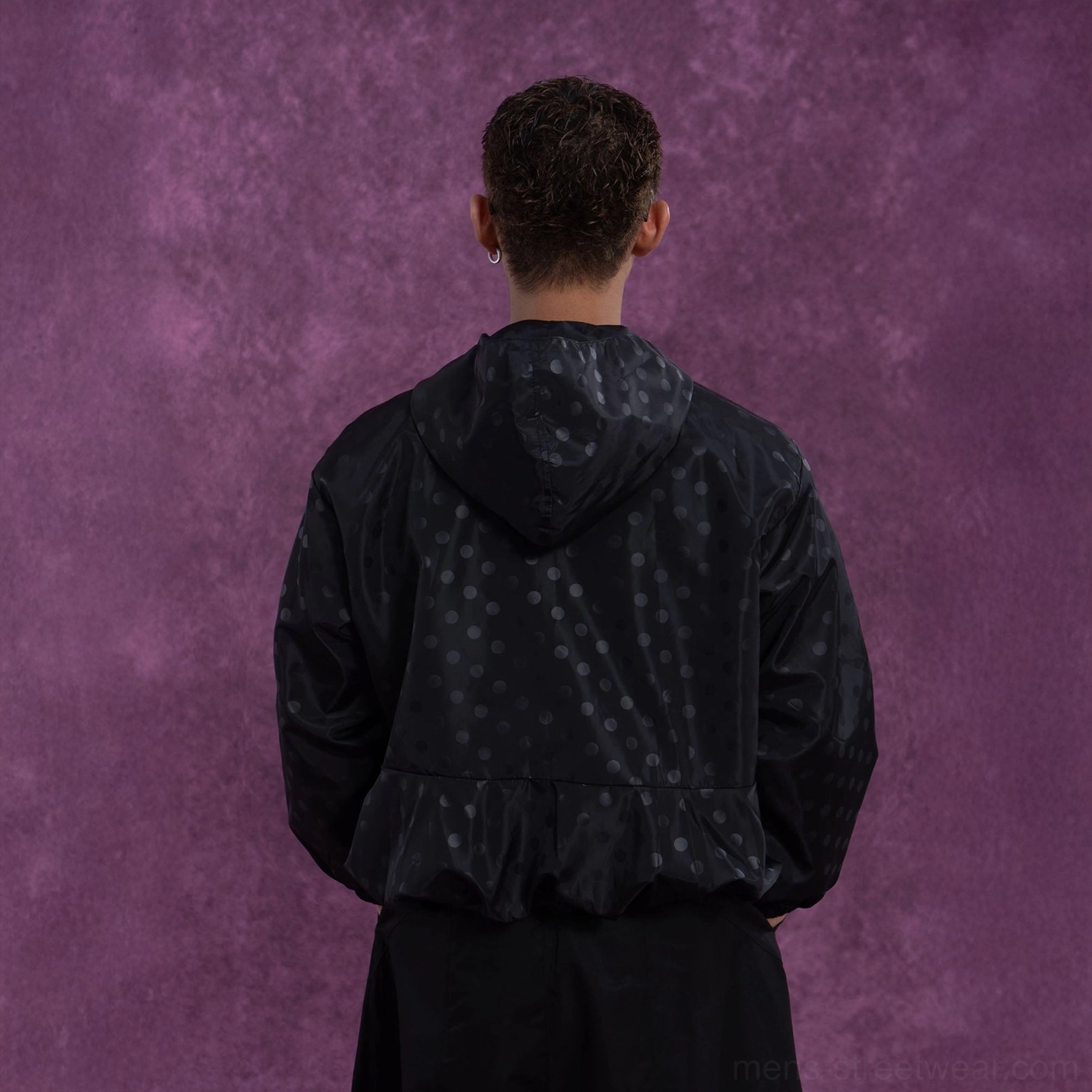 Black tonal polka dot hooded windbreaker jacket back view showing elasticated hem and relaxed streetwear silhouette