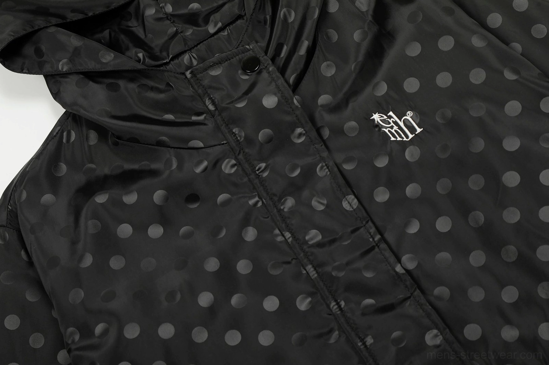 Close up of black polka dot hooded windbreaker fabric embroidered chest detail and front snap closure