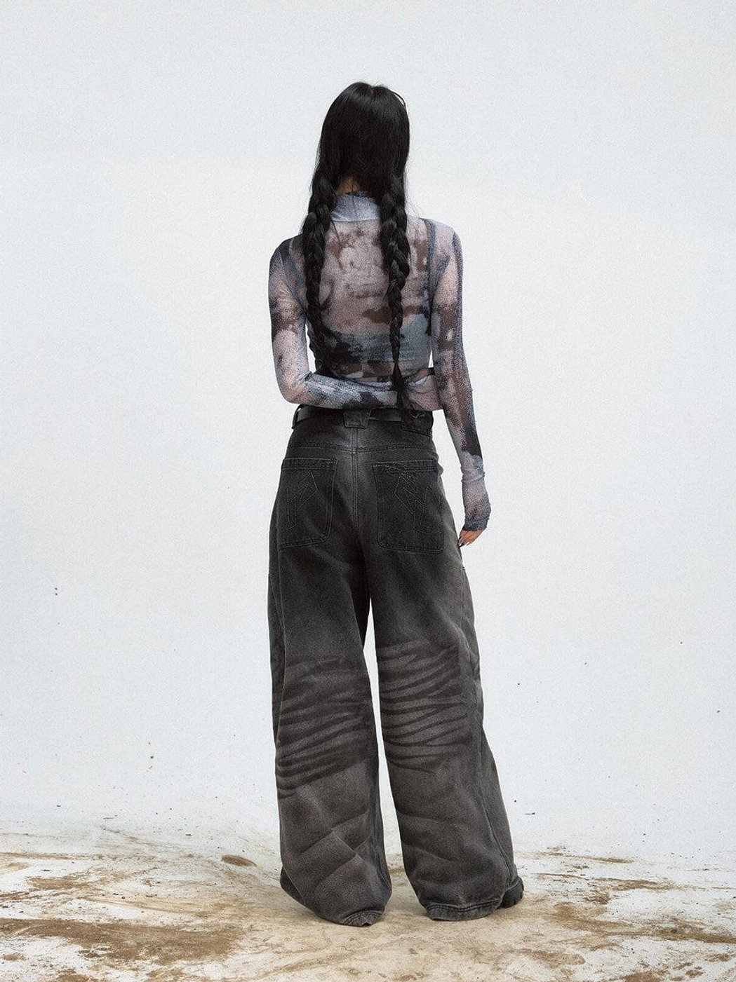 Back view of a long-sleeve black printed mesh turtleneck sweatshirt styled with wide-leg black jeans
