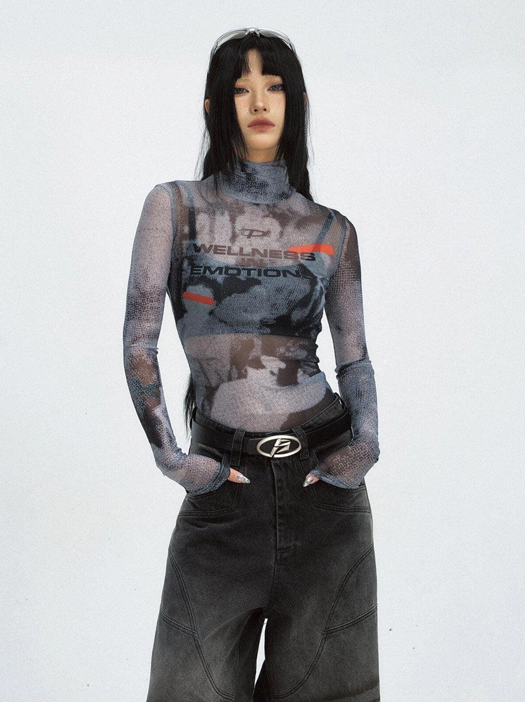 Female model wearing a slim-fit black printed mesh turtleneck sweatshirt with wide-leg jeans and streetwear belt