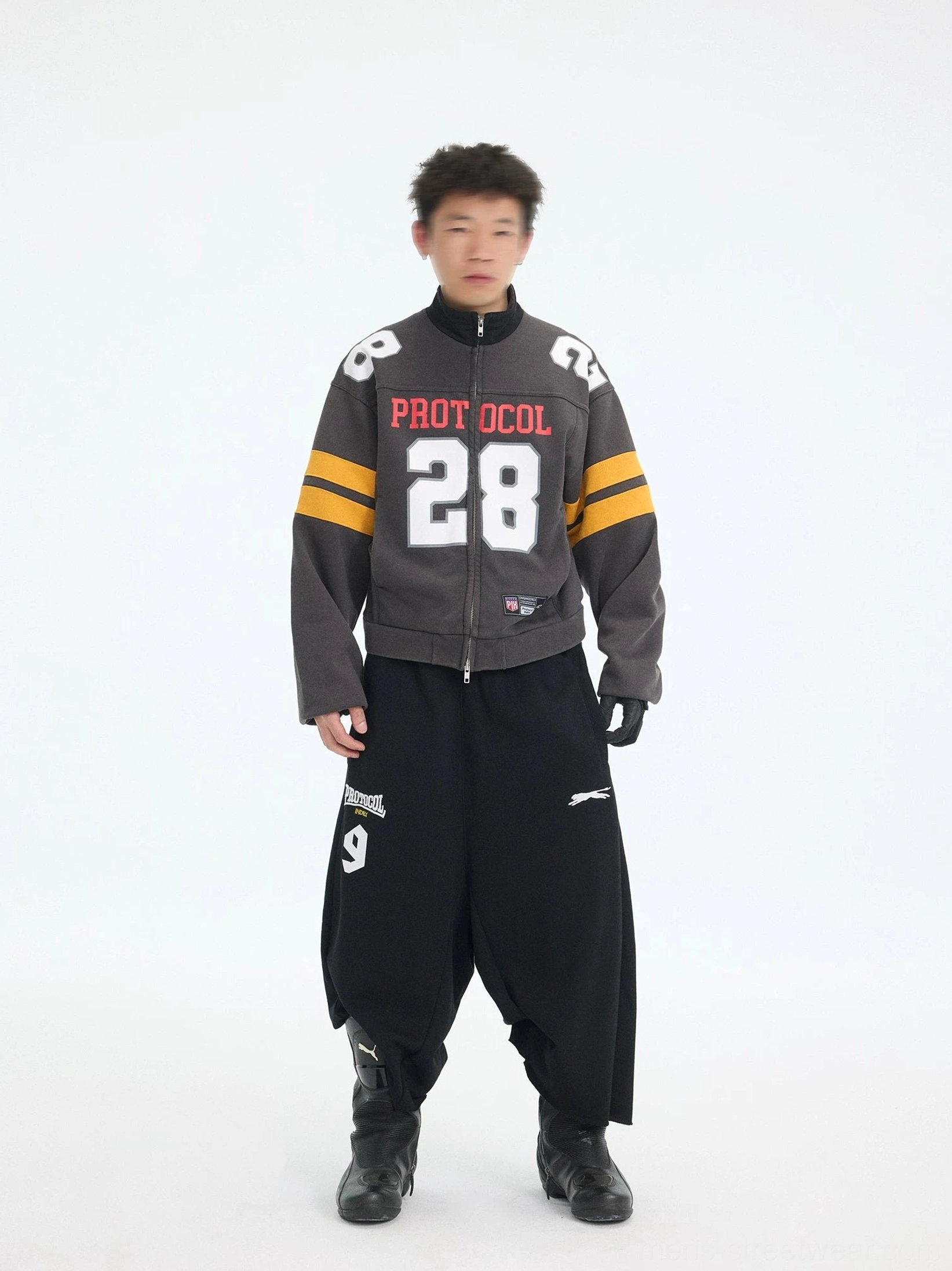 Male model wearing black PROTOCOL 9 oversized court shorts with cropped football jersey, leather gloves, and biker boots