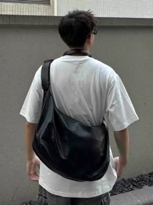 Black PU crescent crossbody shoulder bag shown from the rear three-quarter angle with a wide adjustable strap and soft unstructured shape
