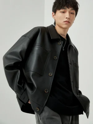 Black oversized cropped PU leather jacket with square neckline front three-quarter view on male model wearing minimalist casual styling