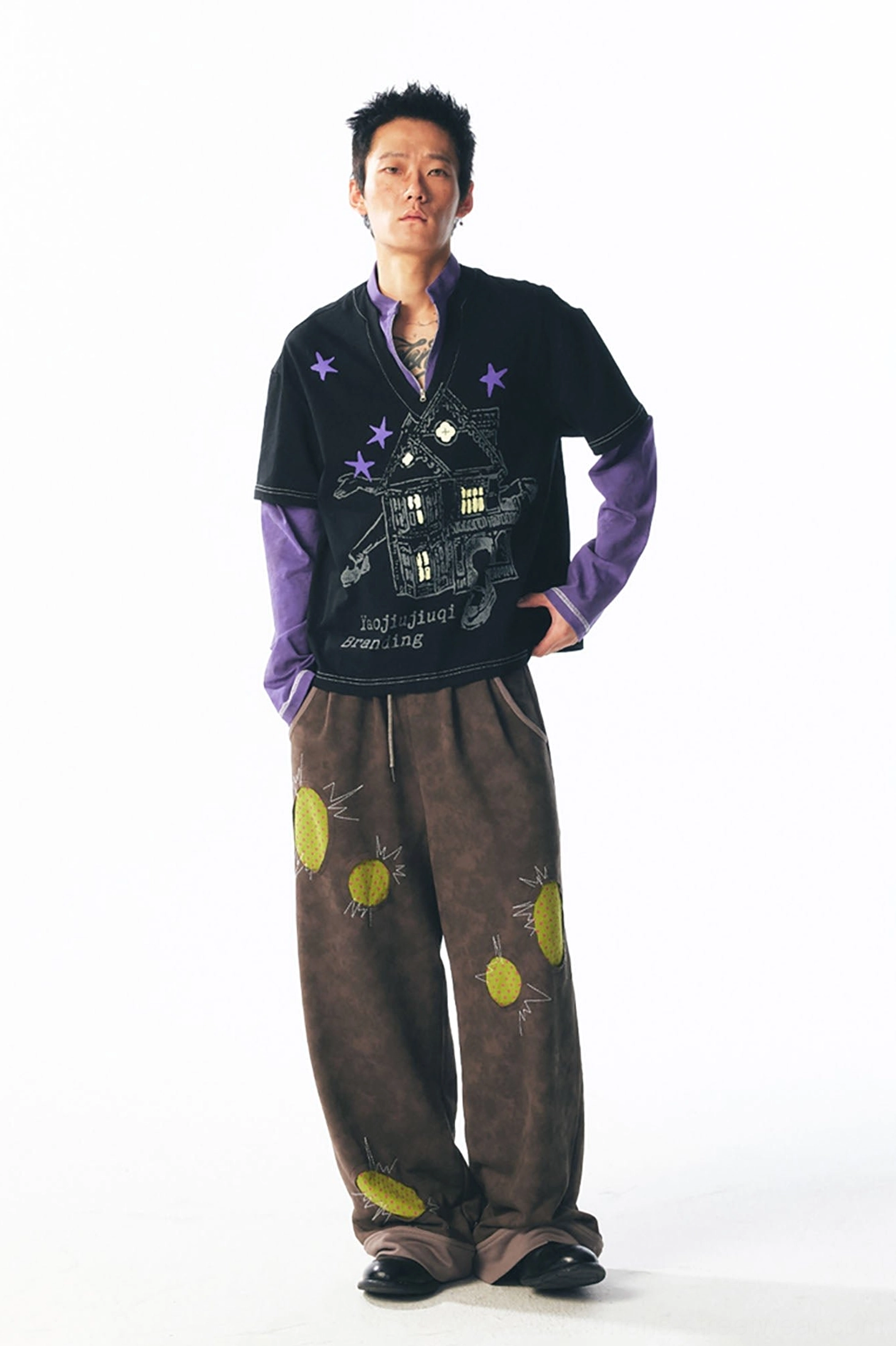 Rear three-quarter view of a relaxed black short sleeve over purple long sleeve graphic streetwear top