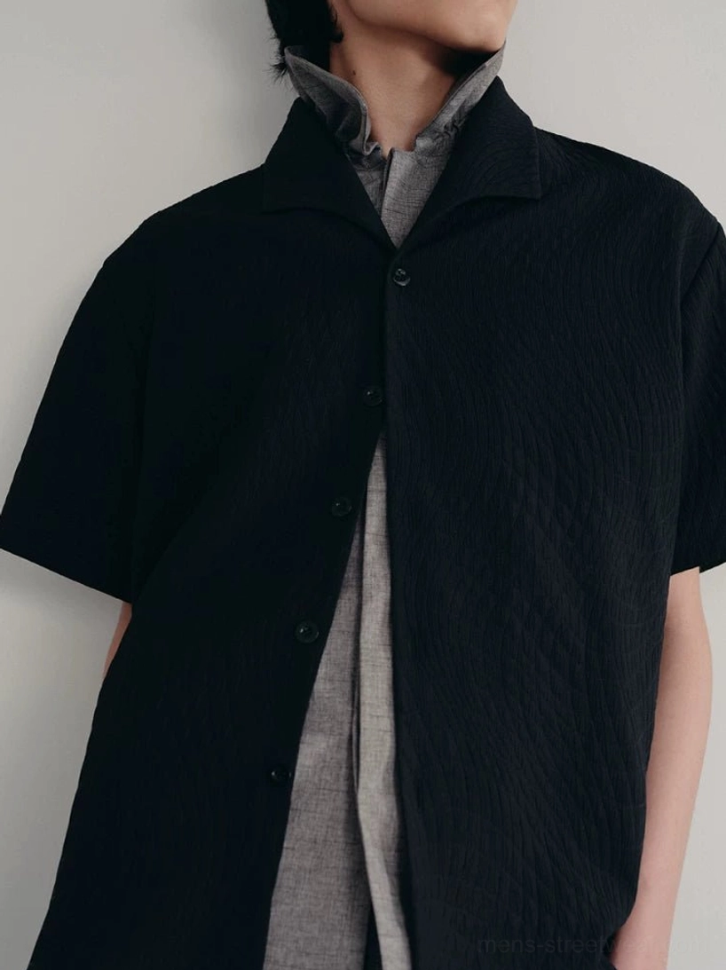Close-up of black quilted camp collar shirt with wave texture button placket and layered gray collared top