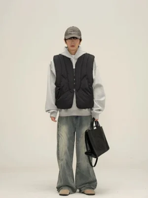 Black quilted puffer vest styled with a gray hoodie wide-leg jeans baseball cap and black tote bag in a Korean streetwear outfit
