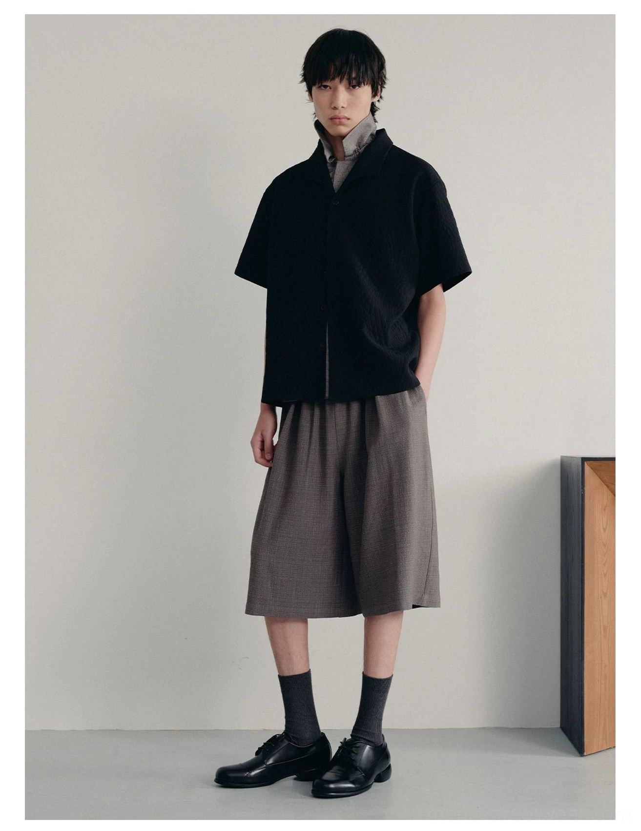 Black quilted short sleeve camp shirt styled with gray cropped wide leg shorts loafers and crew socks