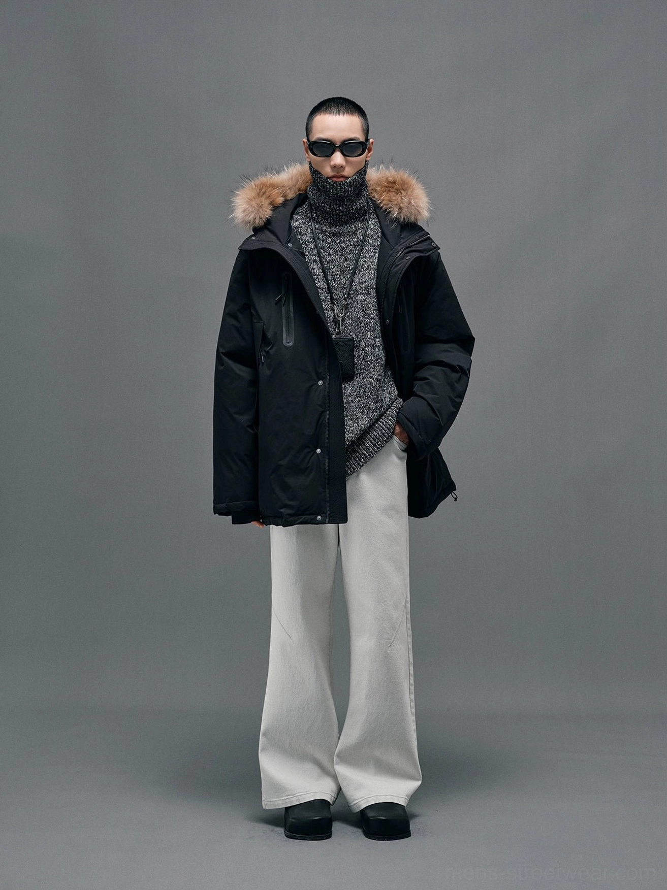 Black hooded down coat with plush raccoon fur collar shown in a full front studio outfit with white wide-leg trousers