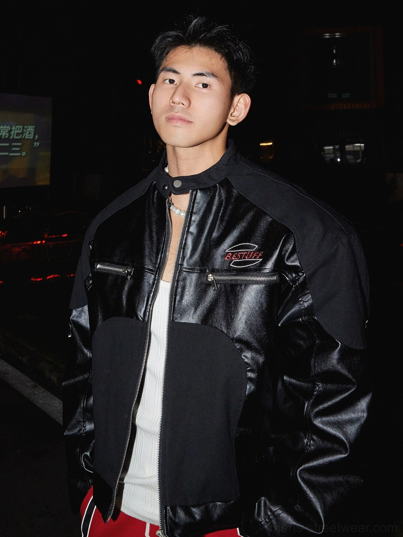Black racing panel zip-up winter jacket close-up showing glossy contrast panels chest zip pockets and stand collar