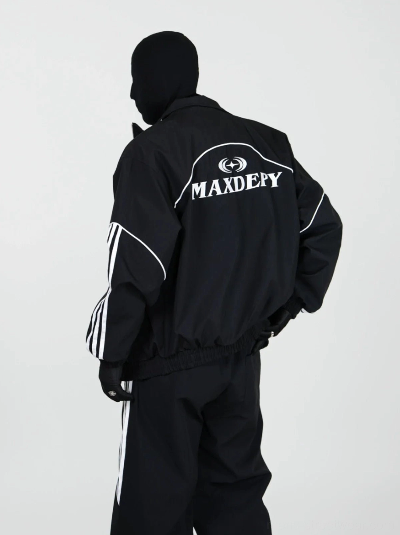 Back view of black racing tracksuit set with white piping striped sleeves wide-leg pants and graphic back print