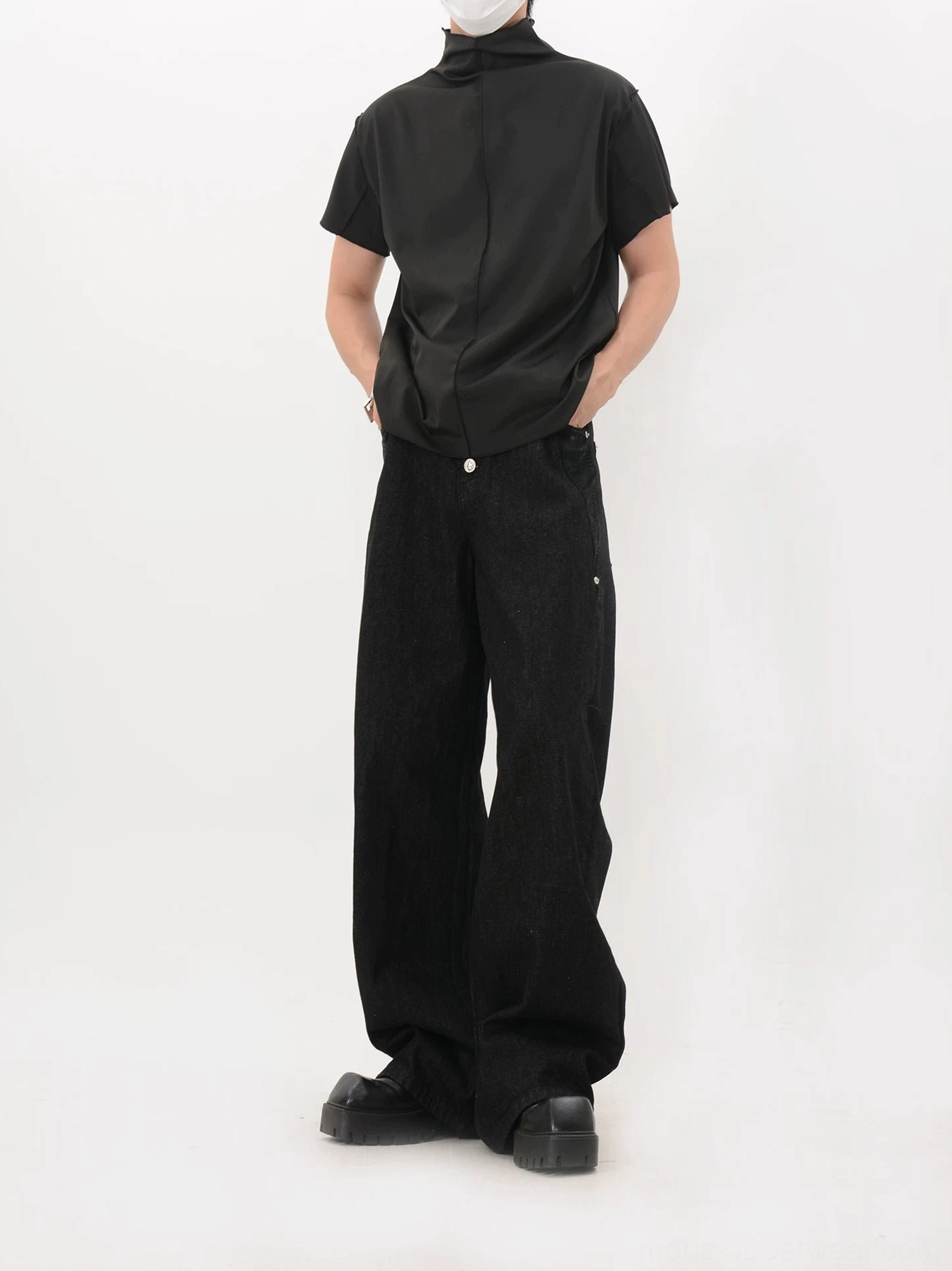 Black relaxed fit back seam mock neck shirt shown from the rear with hands in pockets, wide-leg jeans, and leather shoes