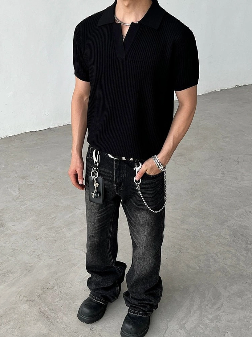 Full-body view of a model wearing a black relaxed-fit ribbed knit polo shirt with washed black jeans leather shoes and chain accessories