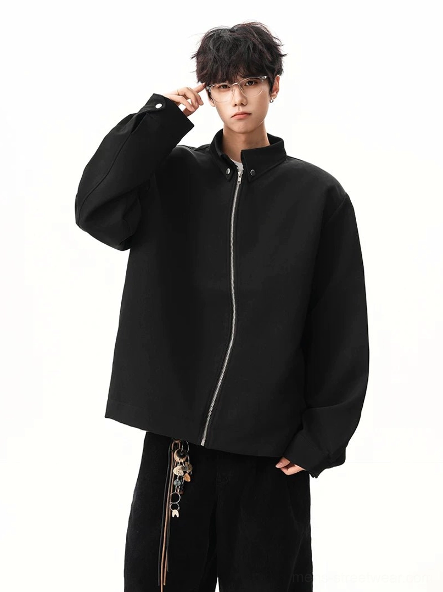 Full body front view of black relaxed fit stand collar zip jacket with dropped shoulders in minimalist studio setting